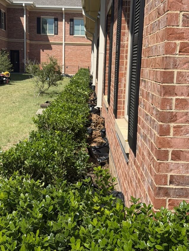 Foundation work along the landscaped side of a brick building