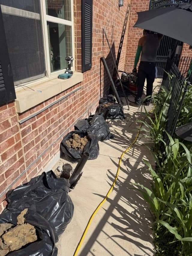 Pier holes and tools lined up along a brick home during a foundation repair